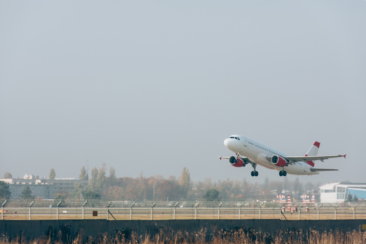 Jet plane above airport runway with cloudy sky at background
